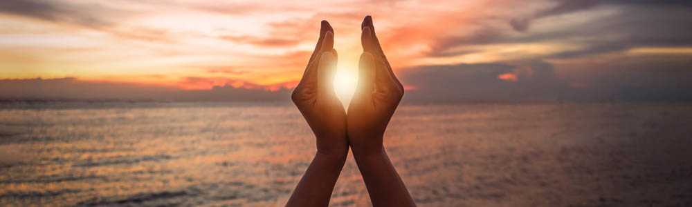 Hands holding the sun at sunset on a beach